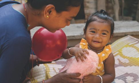 A mother handing her daughter a pink plush toy.