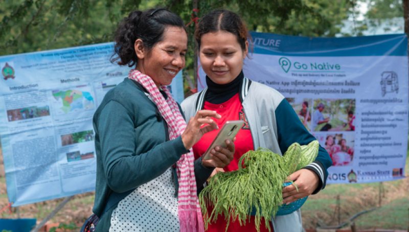 Two women farmers taking a photo of their crops